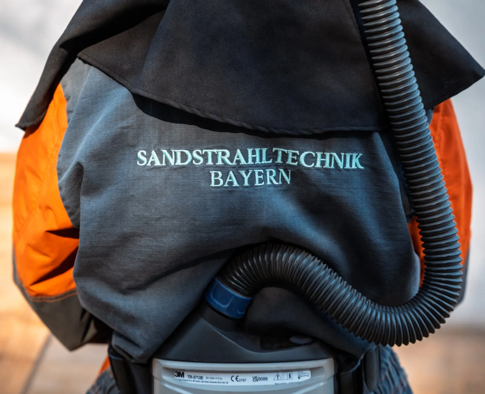 Rücken eines Strahlanzugs mit dem Logo von Sandstrahltechnik Bayern