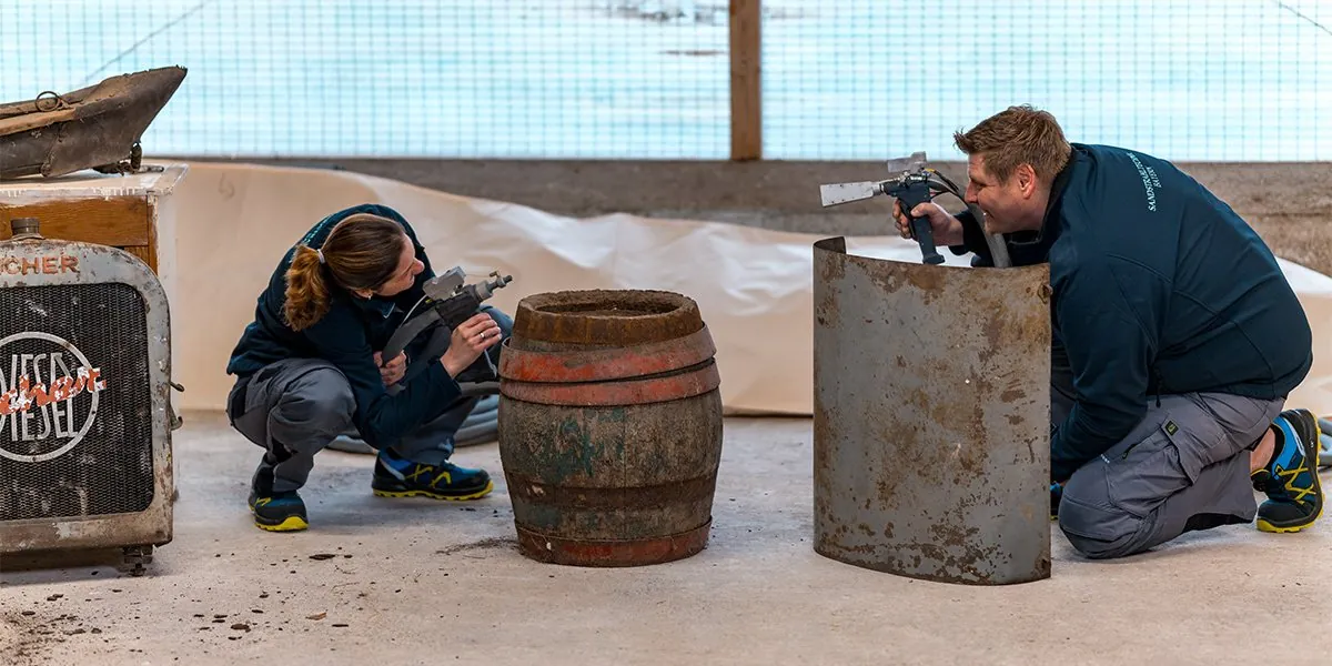 Thomas und Manuela Paulus beim Sandstrahlen von Fass und Blechtonne